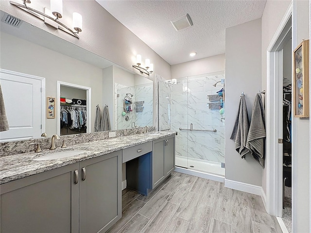 655 Conservation Blvd, Groveland, FL 34736 - bathroom with a walk in closet, double vanity, a stall shower, wood finished floors, and a textured ceiling