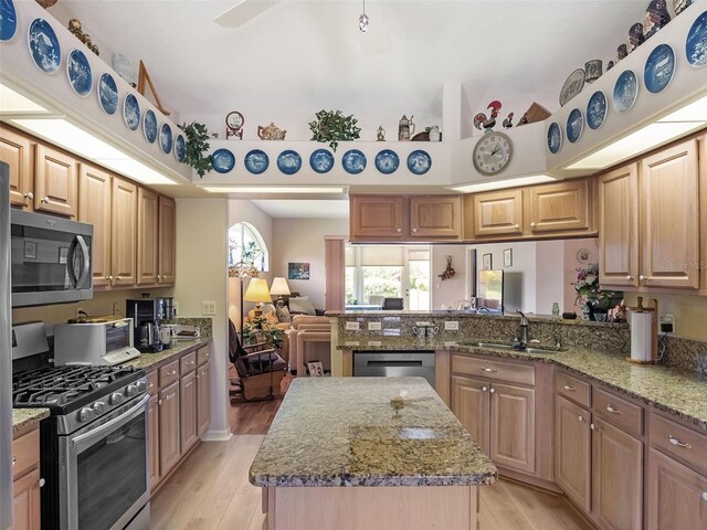 4814 Saint Andrews Arc, Leesburg, FL 34748 - kitchen featuring stainless steel appliances, light wood finished floors, light stone countertops, and a kitchen island