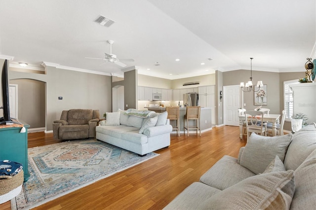 2465 Violet Ct, The Villages, FL 32162 - living room featuring arched walkways, ceiling fan, light wood finished floors, crown molding, and a chandelier