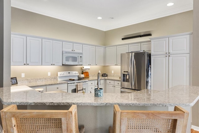 2465 Violet Ct, The Villages, FL 32162 - kitchen with white appliances, a kitchen breakfast bar, a peninsula, recessed lighting, and white cabinetry