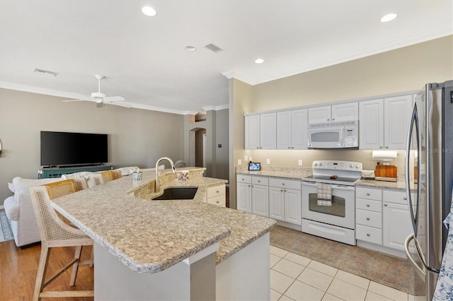 2465 Violet Ct, The Villages, FL 32162 - kitchen with white appliances, arched walkways, ornamental molding, white cabinetry, and an island with sink
