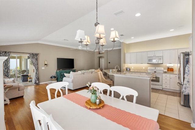 2465 Violet Ct, The Villages, FL 32162 - dining room featuring ornamental molding, light wood-style floors, vaulted ceiling, ceiling fan, and a chandelier
