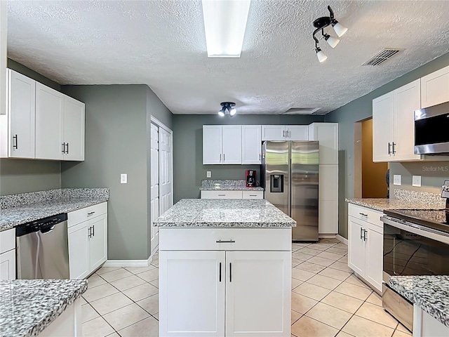 45 Forest Ln, Bronson, FL 32621 - kitchen with stainless steel appliances, light tile patterned floors, a textured ceiling, a kitchen island, and white cabinets