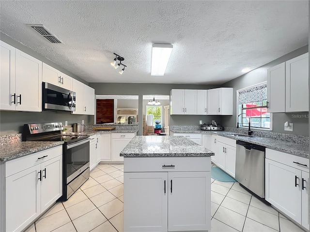 45 Forest Ln, Bronson, FL 32621 - kitchen with stainless steel appliances, a center island, healthy amount of natural light, light tile patterned floors, and a textured ceiling