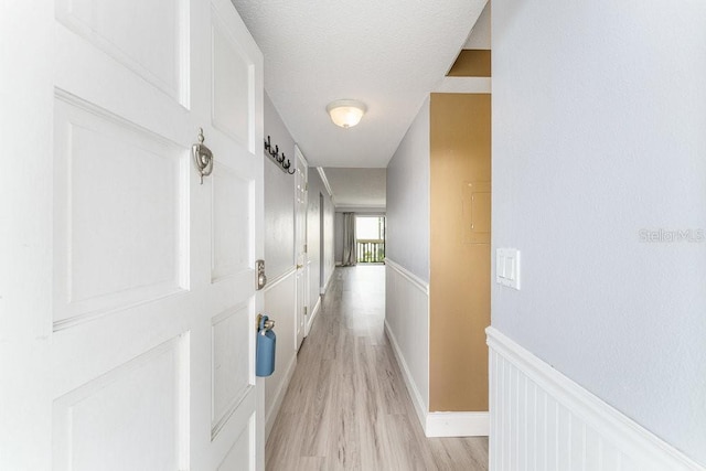 101 N Grandview St Unit 205, Mount Dora, FL 32757 - hallway featuring light wood-style flooring, wainscoting, and a textured ceiling