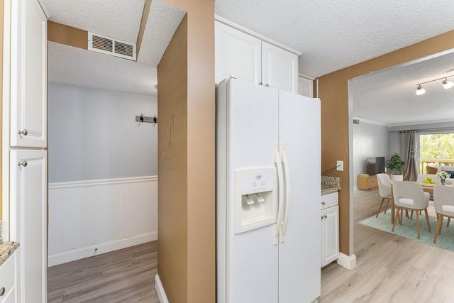 101 N Grandview St Unit 205, Mount Dora, FL 32757 - kitchen with white refrigerator with ice dispenser, a textured ceiling, light wood-style floors, white cabinets, and light stone counters