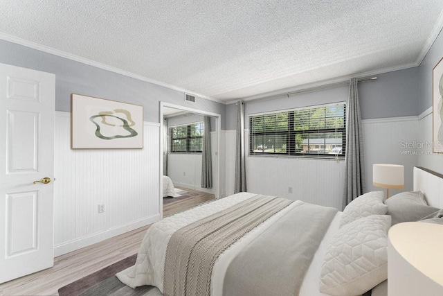 101 N Grandview St Unit 205, Mount Dora, FL 32757 - bedroom with wood finished floors, a textured ceiling, wainscoting, and ornamental molding