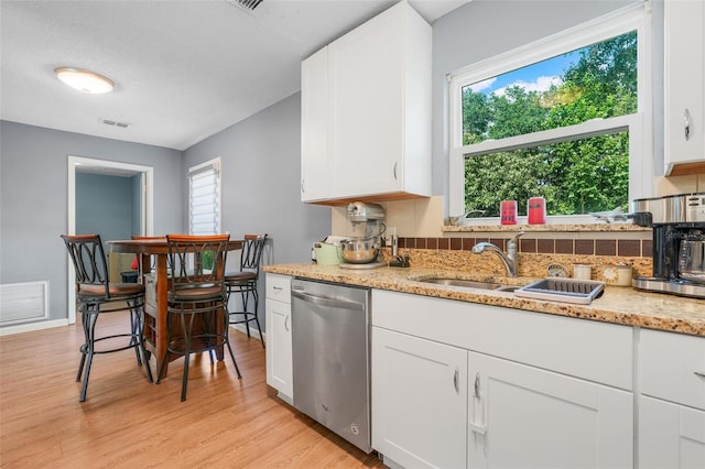 323 Savage Way, Groveland, FL 34736 - kitchen featuring stainless steel dishwasher, healthy amount of natural light, white cabinetry, and light wood-style floors