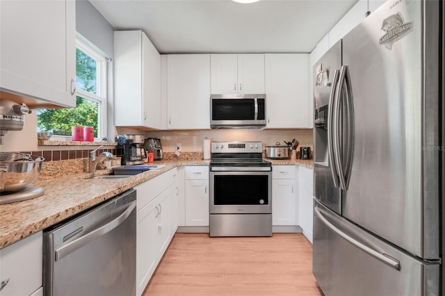 323 Savage Way, Groveland, FL 34736 - kitchen with stainless steel appliances, white cabinetry, tasteful backsplash, and light wood-style flooring