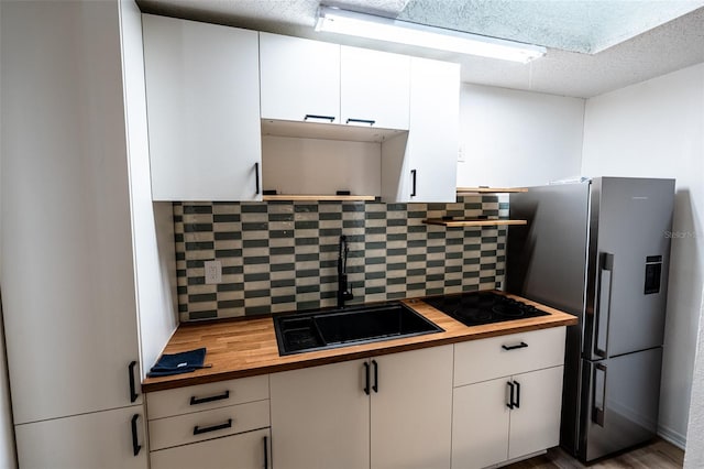 681 Greywood Dr, Altamonte Springs, FL 32701 - kitchen with butcher block countertops, stainless steel fridge, black electric stovetop, backsplash, and white cabinets