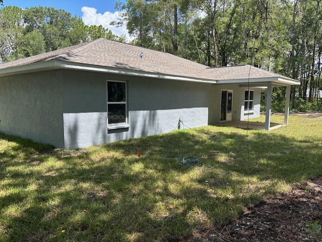 1176 W Bridge Dr, Citrus Springs, FL 34434 - view of side of home featuring a shingled roof, a lawn, stucco siding, and a patio