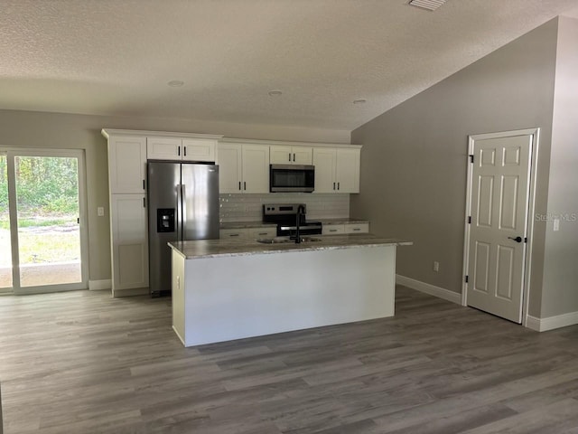 1176 W Bridge Dr, Citrus Springs, FL 34434 - kitchen featuring appliances with stainless steel finishes, a textured ceiling, white cabinetry, vaulted ceiling, and tasteful backsplash