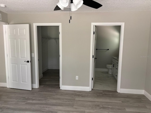 1176 W Bridge Dr, Citrus Springs, FL 34434 - unfurnished bedroom featuring a walk in closet, a textured ceiling, a closet, ensuite bath, and a ceiling fan