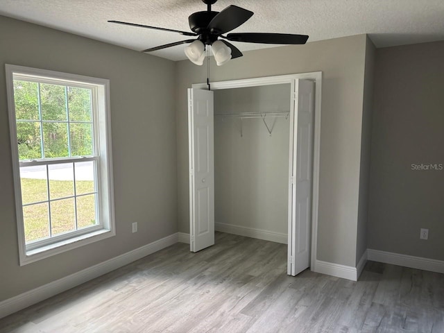 1176 W Bridge Dr, Citrus Springs, FL 34434 - unfurnished bedroom featuring multiple windows, wood finished floors, a textured ceiling, a closet, and ceiling fan