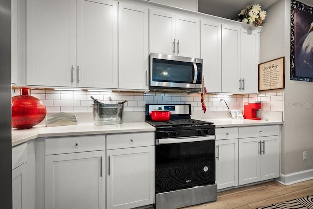1055 Rustic Mill Dr, Saint Augustine, FL 32092 - kitchen featuring stainless steel appliances, light countertops, decorative backsplash, white cabinets, and light wood-style flooring