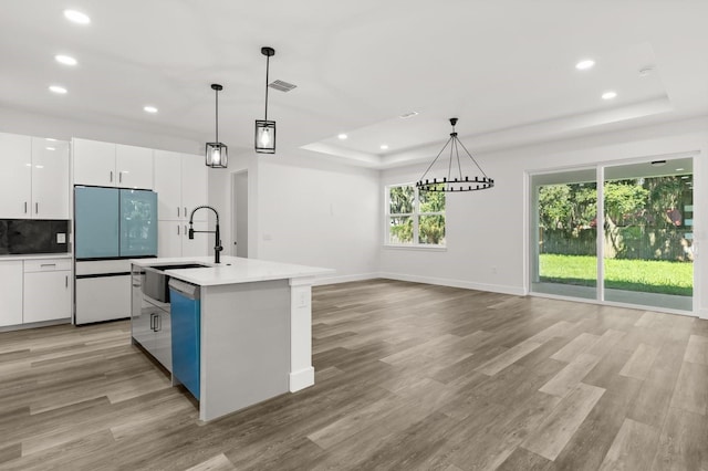 321 Watershore Dr, Leesburg, FL 34748 - kitchen with white fridge, a raised ceiling, light wood-style flooring, recessed lighting, and white cabinetry