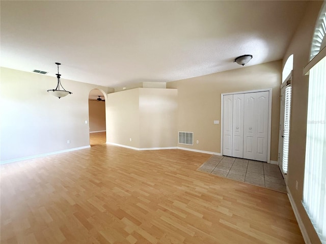 3416 Capland Ave, Clermont, FL 34711 - unfurnished living room featuring light wood-type flooring, arched walkways, and healthy amount of natural light