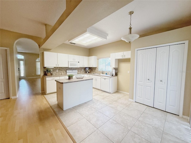 3416 Capland Ave, Clermont, FL 34711 - kitchen featuring white appliances, a kitchen island, arched walkways, white cabinetry, and light countertops