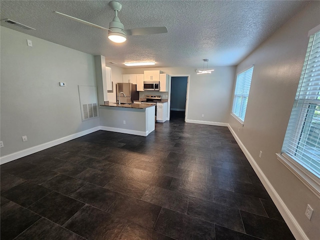 711 Sugar Bay Way Unit 115, Lake Mary, FL 32746 - kitchen featuring appliances with stainless steel finishes, dark countertops, a textured ceiling, a peninsula, and white cabinetry
