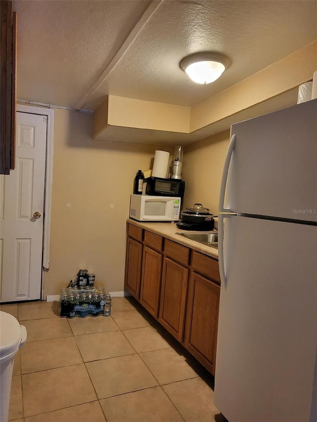 2611 Hiawatha Ave, Sanford, FL 32773 - kitchen featuring white appliances, brown cabinets, a textured ceiling, light tile patterned floors, and light countertops