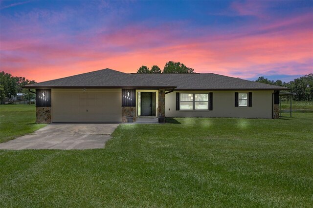 14325 Manchester Ave, Groveland, FL 34736 - ranch-style house featuring an attached garage, concrete driveway, a lawn, and stone siding