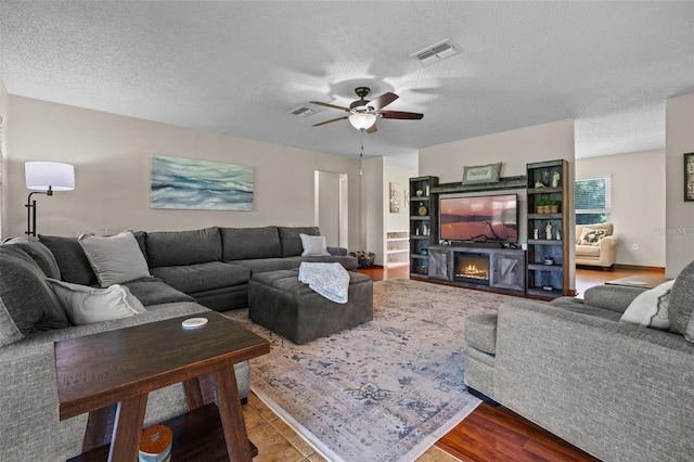14325 Manchester Ave, Groveland, FL 34736 - living room with ceiling fan, a textured ceiling, a warm lit fireplace, and wood finished floors