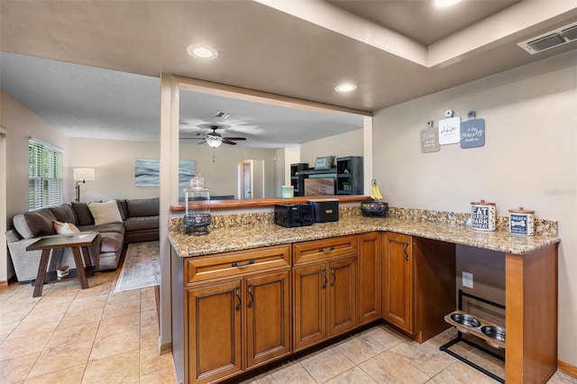 14325 Manchester Ave, Groveland, FL 34736 - kitchen featuring brown cabinets, open floor plan, ceiling fan, light stone counters, and recessed lighting