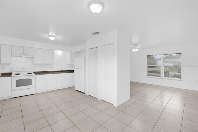 302 W Rose Ln, Lady Lake, FL 32159 - kitchen with white appliances, under cabinet range hood, dark countertops, white cabinets, and light tile patterned floors