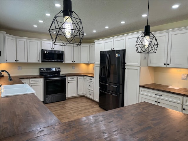 219 Magnolia Cir, Eustis, FL 32726 - kitchen with black appliances, wooden counters, recessed lighting, wood finished floors, and white cabinetry