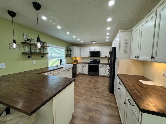 219 Magnolia Cir, Eustis, FL 32726 - kitchen featuring black appliances, wood counters, a peninsula, recessed lighting, and a textured ceiling