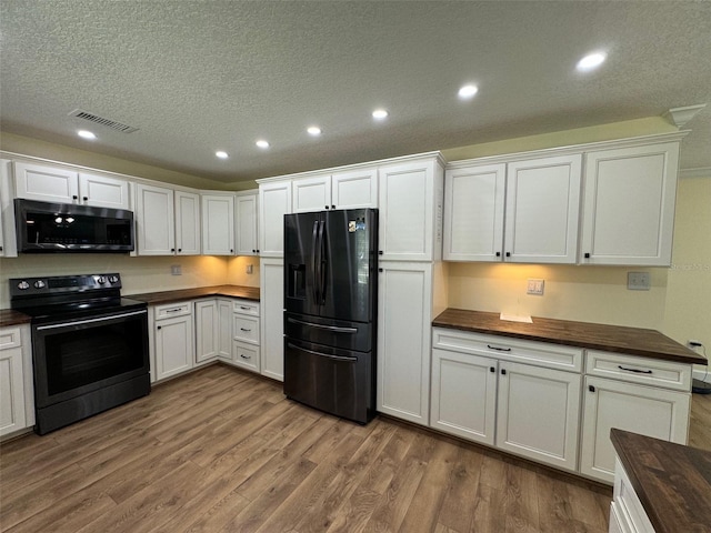 219 Magnolia Cir, Eustis, FL 32726 - kitchen featuring black appliances, wood finished floors, wooden counters, recessed lighting, and white cabinetry