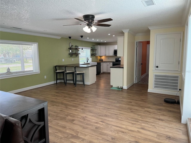 219 Magnolia Cir, Eustis, FL 32726 - kitchen featuring dark countertops, black appliances, a breakfast bar area, ceiling fan, and a peninsula