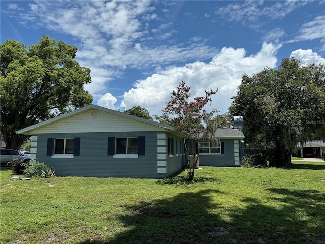 219 Magnolia Cir, Eustis, FL 32726 - view of side of home featuring a yard, brick siding, and a chimney