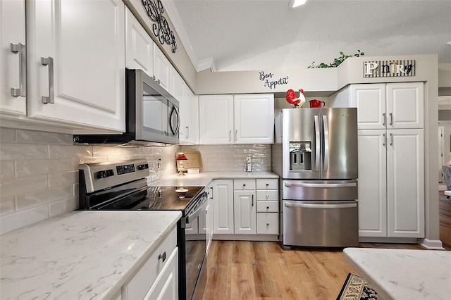 1309 Corona Ave, The Villages, FL 32159 - kitchen with appliances with stainless steel finishes, white cabinets, light wood-style floors, crown molding, and lofted ceiling