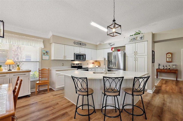 1309 Corona Ave, The Villages, FL 32159 - kitchen with stainless steel appliances, a textured ceiling, light countertops, white cabinets, and an island with sink