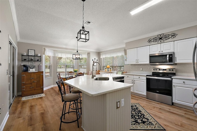 1309 Corona Ave, The Villages, FL 32159 - kitchen with stainless steel appliances, crown molding, white cabinets, light wood-type flooring, and backsplash