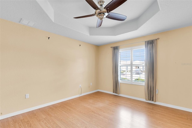 12407 NE 48th Loop, Oxford, FL 34484 - empty room featuring a raised ceiling, light wood-type flooring, and ceiling fan