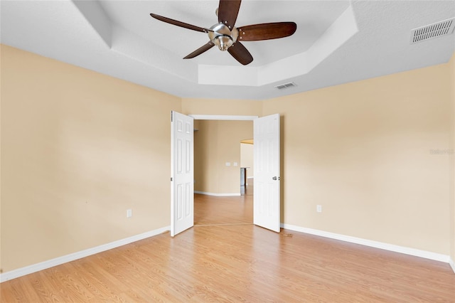 12407 NE 48th Loop, Oxford, FL 34484 - empty room with a raised ceiling, ceiling fan, and light wood-style flooring