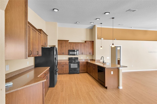 12407 NE 48th Loop, Oxford, FL 34484 - kitchen featuring black appliances, a peninsula, light wood-style floors, brown cabinets, and decorative light fixtures