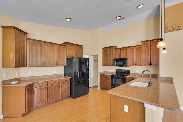 12407 NE 48th Loop, Oxford, FL 34484 - kitchen featuring black appliances, a peninsula, light wood finished floors, brown cabinetry, and a breakfast bar area