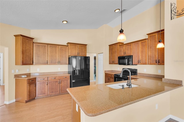 12407 NE 48th Loop, Oxford, FL 34484 - kitchen featuring black appliances, a peninsula, brown cabinets, light wood finished floors, and high vaulted ceiling