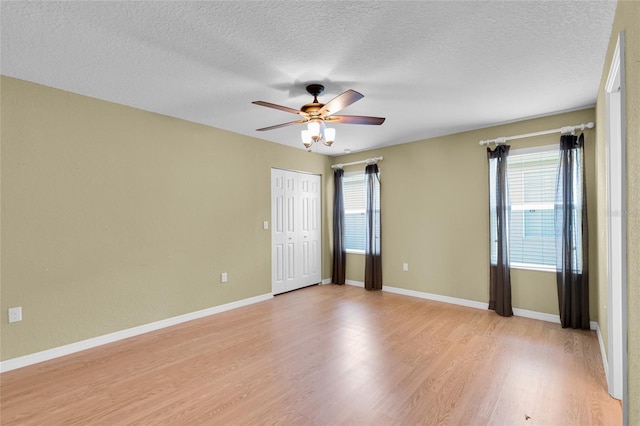 12407 NE 48th Loop, Oxford, FL 34484 - empty room with healthy amount of natural light, light wood-style flooring, ceiling fan, and a textured ceiling