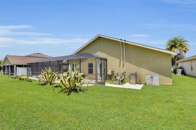 12407 NE 48th Loop, Oxford, FL 34484 - rear view of house with a lawn, stucco siding, a patio area, and glass enclosure