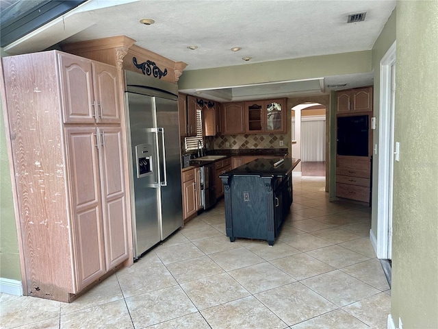 1096 Linkside Ct, Apopka, FL 32712 - kitchen with stainless steel built in fridge, arched walkways, dark countertops, backsplash, and light tile patterned floors