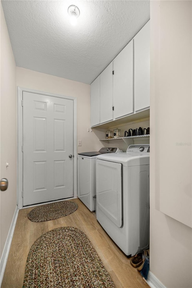 17970 SE 102nd Ct, Summerfield, FL 34491 - laundry room with independent washer and dryer, light wood-style flooring, cabinet space, and a textured ceiling
