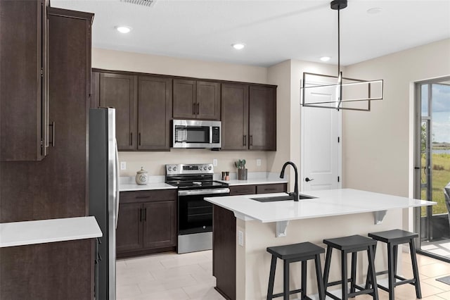 872 Griffon Ave, Lake Alfred, FL 33850 - kitchen with stainless steel appliances, a kitchen breakfast bar, dark brown cabinetry, light countertops, and a kitchen island with sink