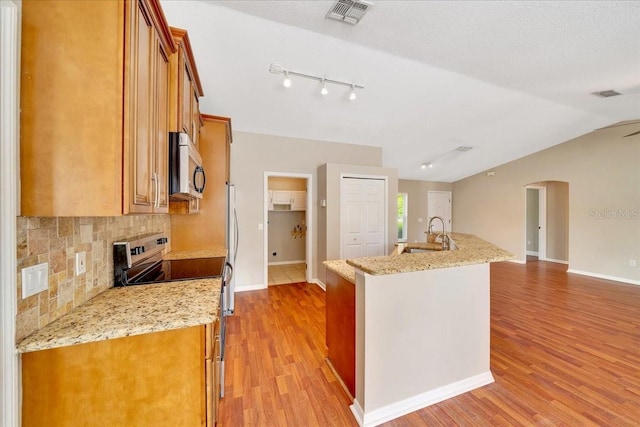 10331 SW 45th Ave, Ocala, FL 34476 - kitchen with stainless steel appliances, brown cabinets, arched walkways, backsplash, and a kitchen island with sink