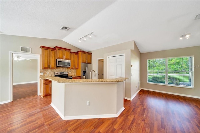 10331 SW 45th Ave, Ocala, FL 34476 - kitchen with appliances with stainless steel finishes, vaulted ceiling, brown cabinetry, decorative backsplash, and wood finished floors