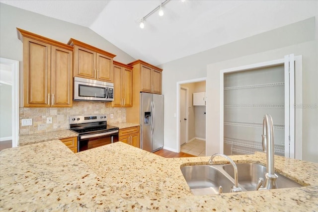 10331 SW 45th Ave, Ocala, FL 34476 - kitchen featuring appliances with stainless steel finishes, lofted ceiling, rail lighting, tasteful backsplash, and light stone counters