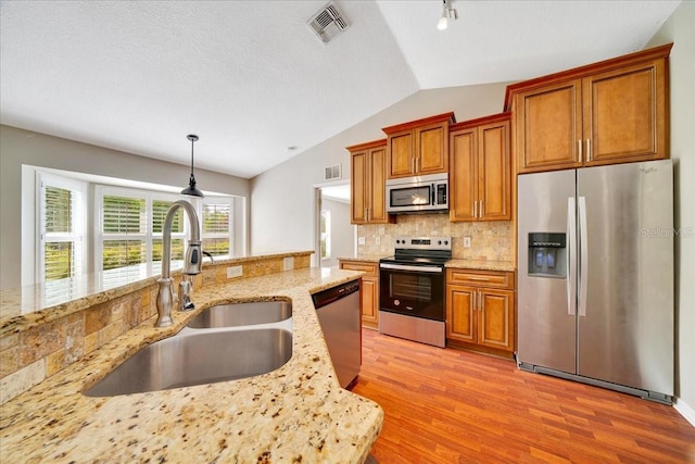 10331 SW 45th Ave, Ocala, FL 34476 - kitchen with stainless steel appliances, lofted ceiling, light wood-style floors, backsplash, and brown cabinets
